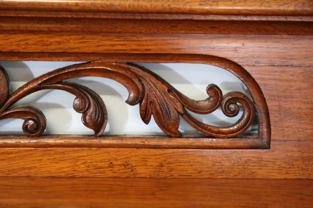 A Victorian pollard oak sideboard featuring a carved upper display shelf, fretwork cresting, and two fielded panel doors with decorative wood grain. View XIV