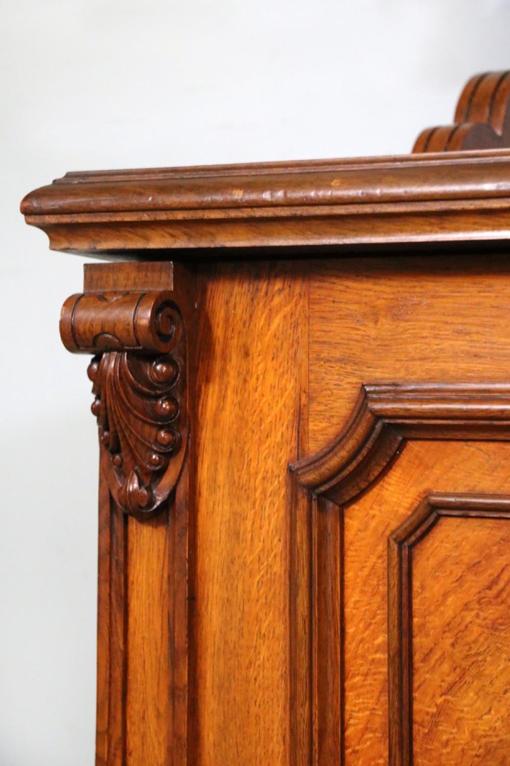 A Victorian pollard oak sideboard featuring a carved upper display shelf, fretwork cresting, and two fielded panel doors with decorative wood grain. View XVI