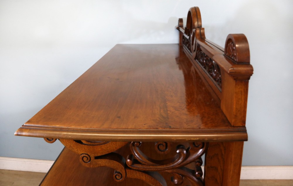 A Victorian pollard oak sideboard featuring a carved upper display shelf, fretwork cresting, and two fielded panel doors with decorative wood grain. View XVII
