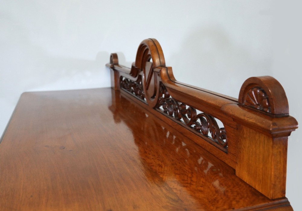 A Victorian pollard oak sideboard featuring a carved upper display shelf, fretwork cresting, and two fielded panel doors with decorative wood grain. View XVIII