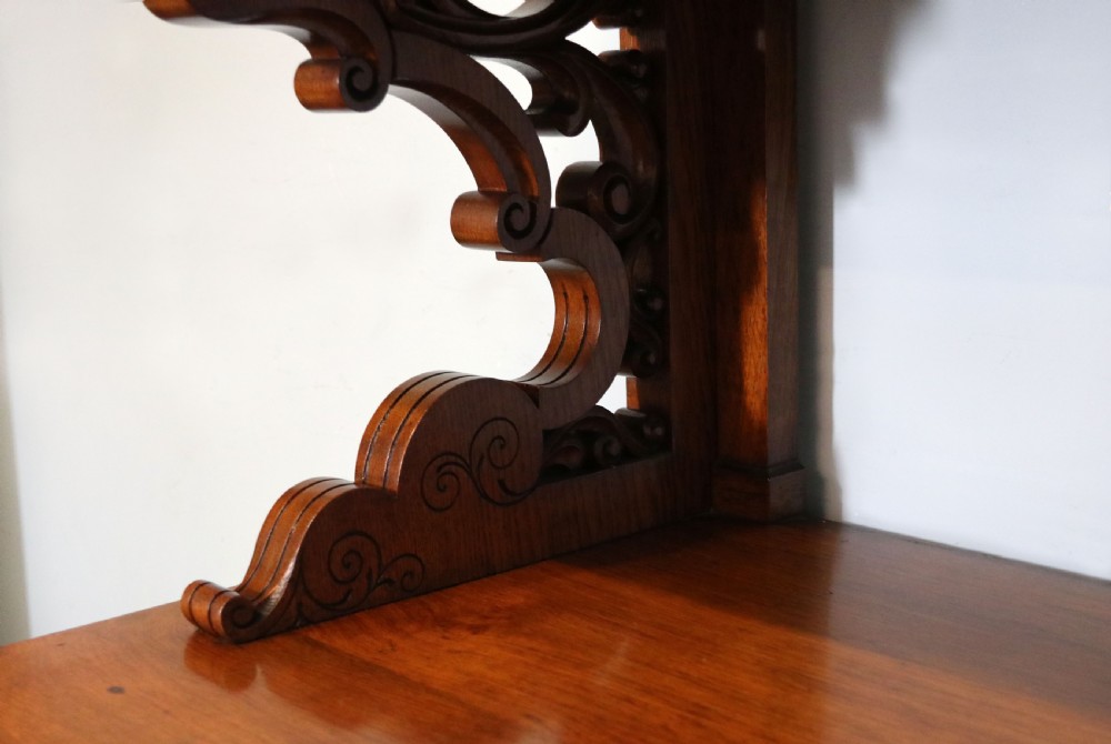 A Victorian pollard oak sideboard featuring a carved upper display shelf, fretwork cresting, and two fielded panel doors with decorative wood grain. View XXI
