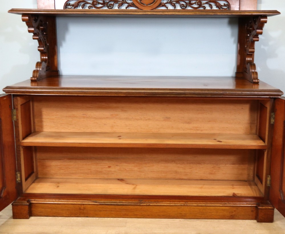 A Victorian pollard oak sideboard featuring a carved upper display shelf, fretwork cresting, and two fielded panel doors with decorative wood grain. View XXVI
