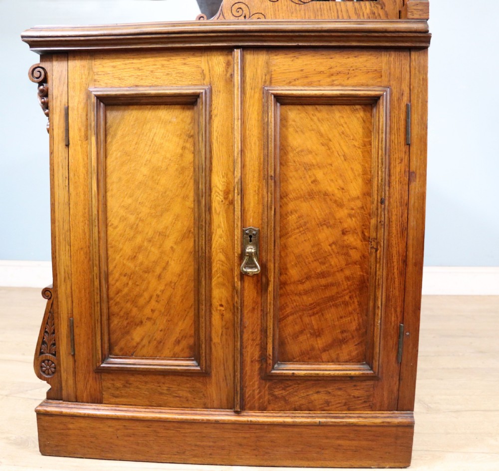 A Victorian pollard oak sideboard featuring a carved upper display shelf, fretwork cresting, and two fielded panel doors with decorative wood grain. View XXXI
