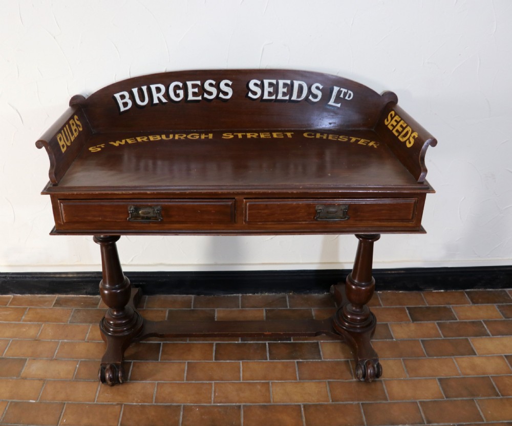 A late Victorian mahogany galleried side table featuring two drawers, turned legs on a trestle base, and painted commercial lettering. View II