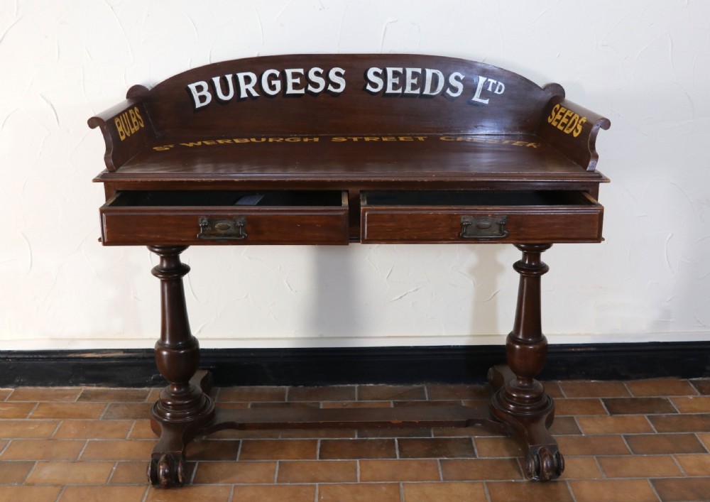 A late Victorian mahogany galleried side table featuring two drawers, turned legs on a trestle base, and painted commercial lettering. View III