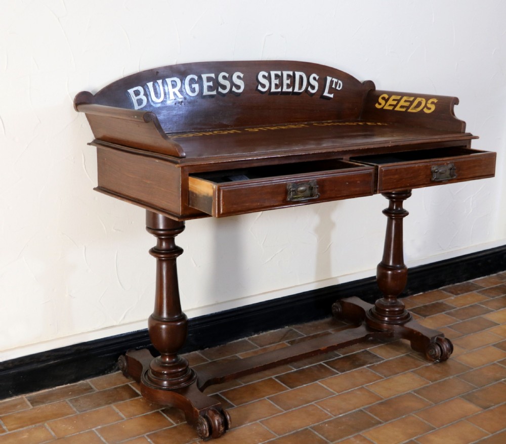 A late Victorian mahogany galleried side table featuring two drawers, turned legs on a trestle base, and painted commercial lettering. View V