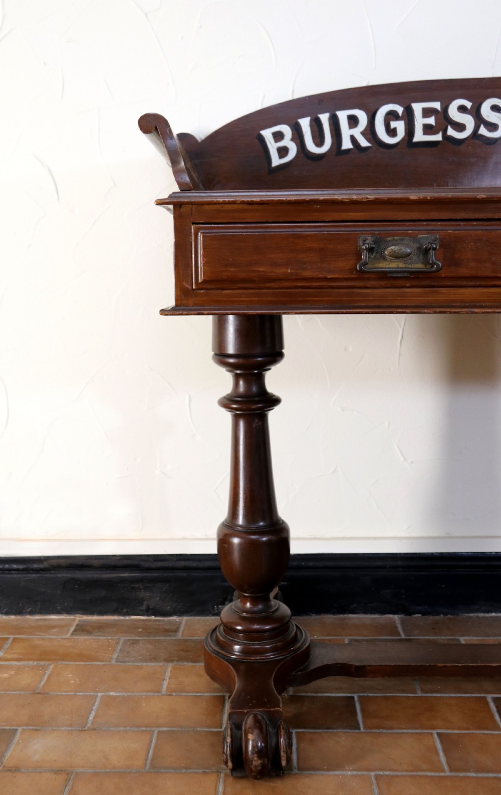 A late Victorian mahogany galleried side table featuring two drawers, turned legs on a trestle base, and painted commercial lettering. View VII