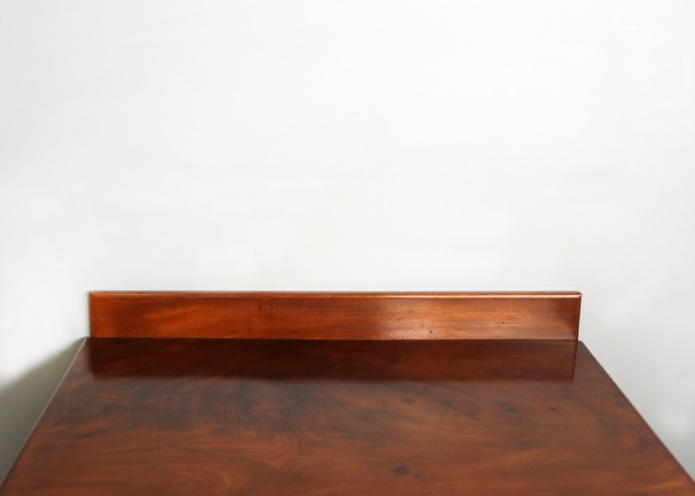An Edwardian mahogany bedside cabinet with a single door containing a central oval marquetry inlay, raised on fluted turned legs. View IX