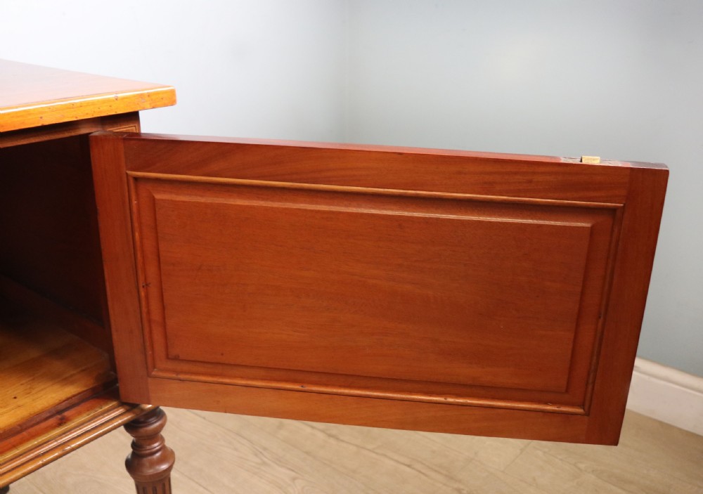 An Edwardian mahogany bedside cabinet with a single door containing a central oval marquetry inlay, raised on fluted turned legs. View XV