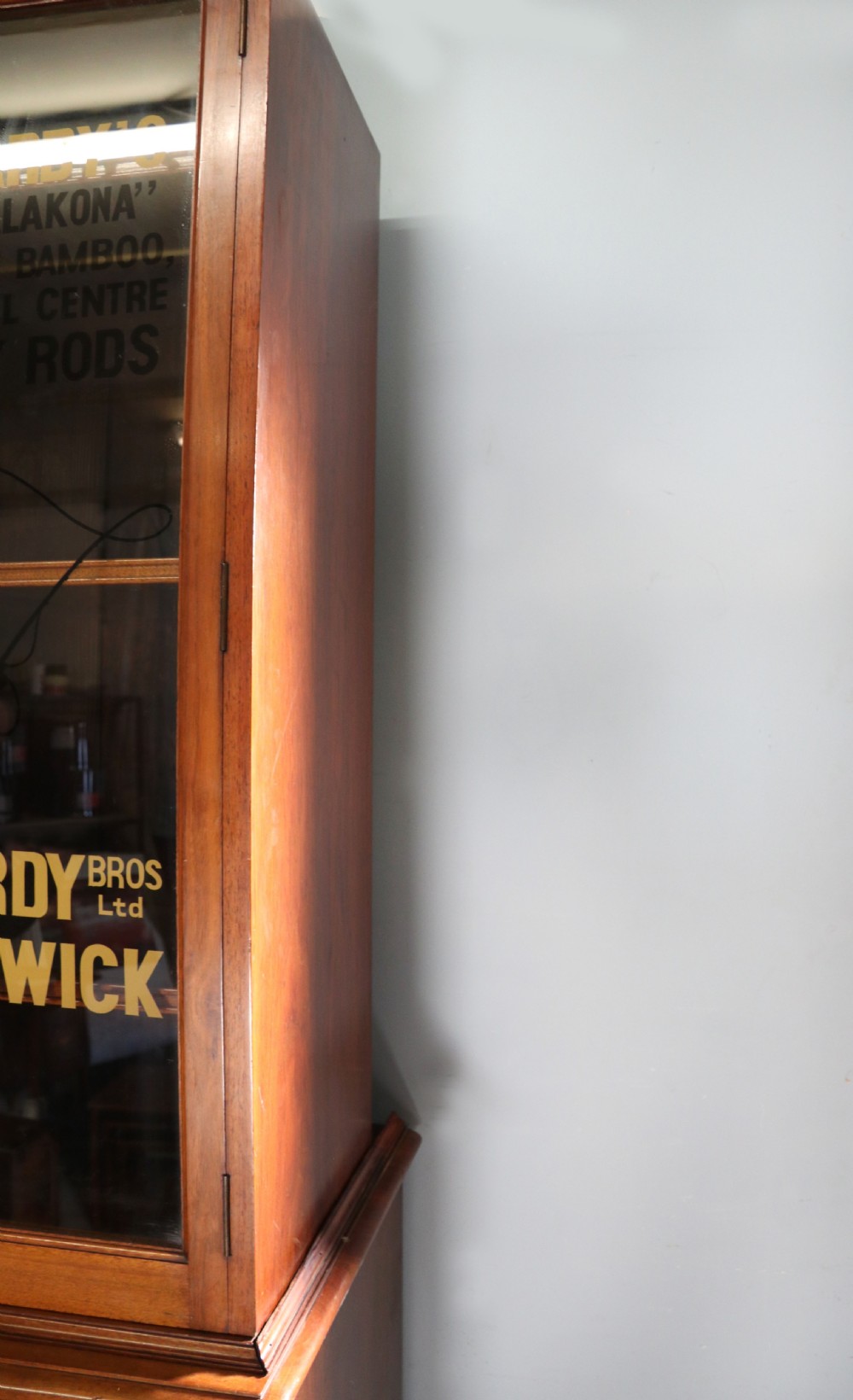 A tall Victorian solid walnut shop cabinet with glazed upper doors featuring sign-written fishing typography, multiple small drawers in the midsection, and panelled cupboard doors below. View XI