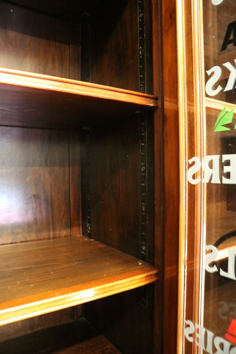 A tall Victorian solid walnut shop cabinet with glazed upper doors featuring sign-written fishing typography, multiple small drawers in the midsection, and panelled cupboard doors below. View XIV