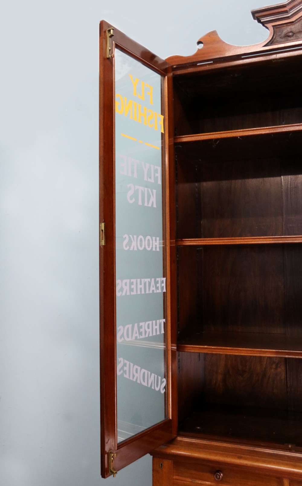 A tall Victorian solid walnut shop cabinet with glazed upper doors featuring sign-written fishing typography, multiple small drawers in the midsection, and panelled cupboard doors below. View XVIII