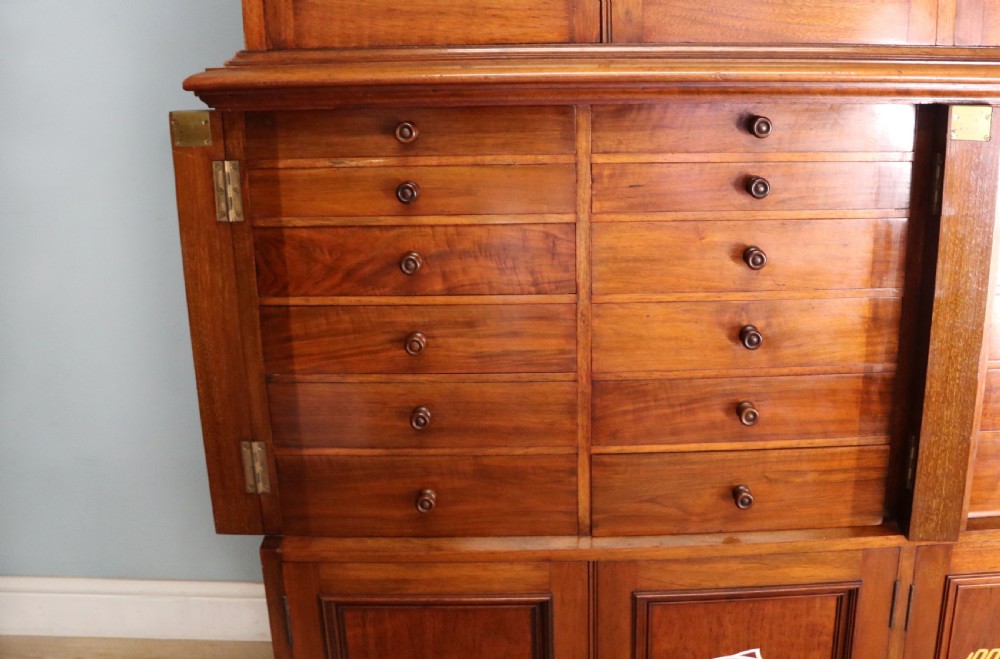A tall Victorian solid walnut shop cabinet with glazed upper doors featuring sign-written fishing typography, multiple small drawers in the midsection, and panelled cupboard doors below. View XIX