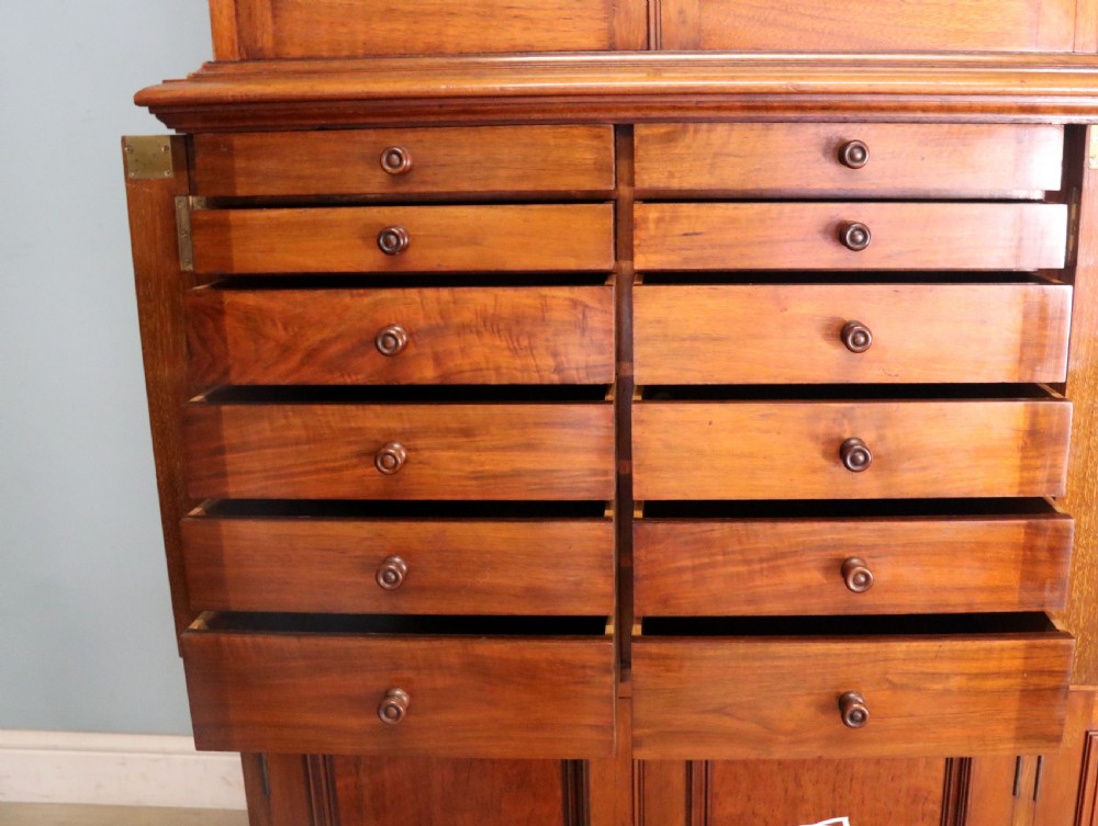 A tall Victorian solid walnut shop cabinet with glazed upper doors featuring sign-written fishing typography, multiple small drawers in the midsection, and panelled cupboard doors below. View XXIII