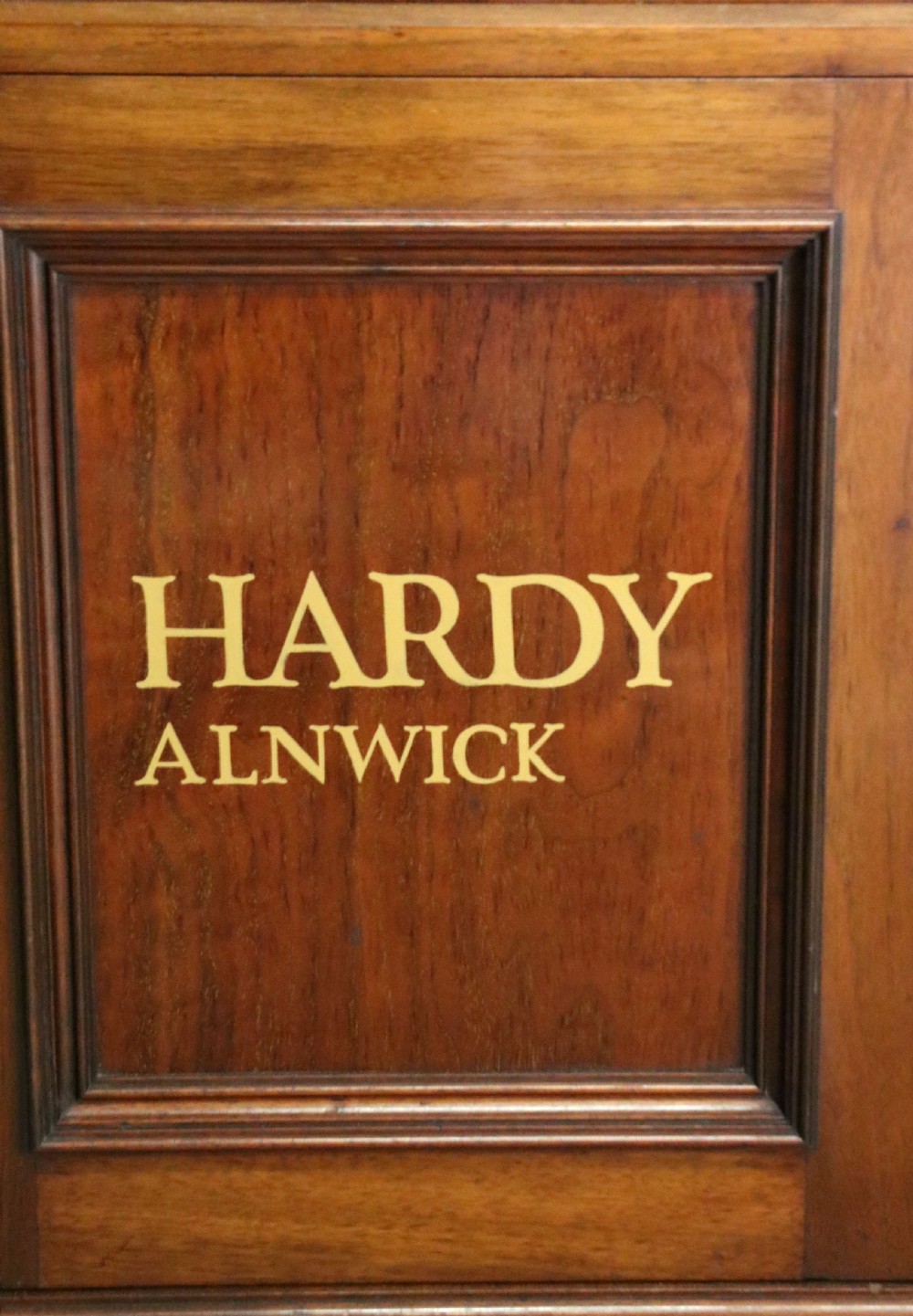 A tall Victorian solid walnut shop cabinet with glazed upper doors featuring sign-written fishing typography, multiple small drawers in the midsection, and panelled cupboard doors below. View XXIX