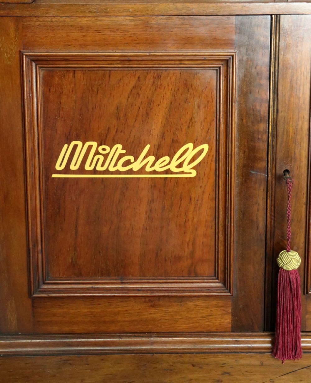 A tall Victorian solid walnut shop cabinet with glazed upper doors featuring sign-written fishing typography, multiple small drawers in the midsection, and panelled cupboard doors below. View XXXI
