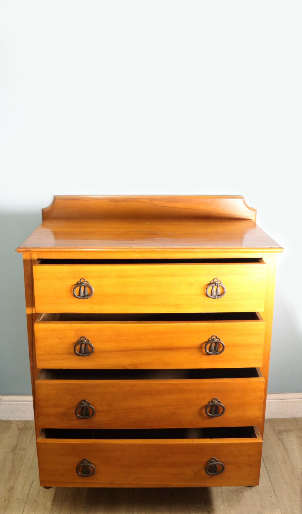 A late Victorian American walnut chest of drawers featuring four full-width drawers with metal drop-ring handles, a low shaped gallery upstand, and turned feet. View II