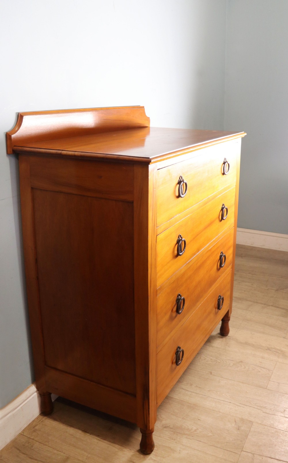 A late Victorian American walnut chest of drawers featuring four full-width drawers with metal drop-ring handles, a low shaped gallery upstand, and turned feet. View III