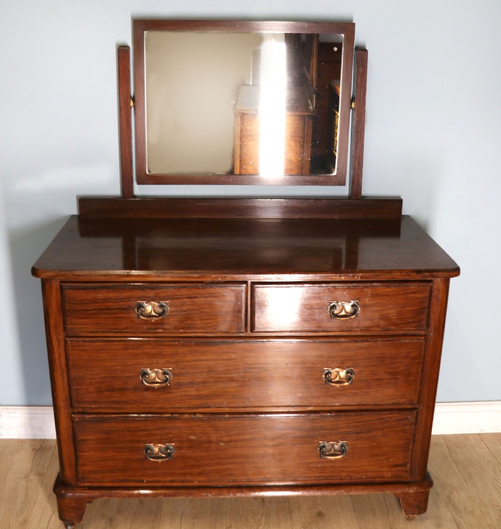 A dark mahogany Victorian dressing chest featuring a rectangular pivoting top mirror and four drawers with metal drop handles.
