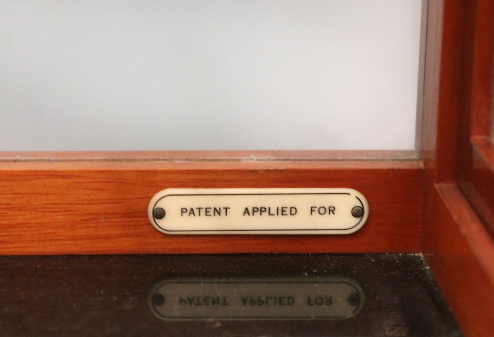 An Oertling precision chemists beam balance scale with a brass mechanism housed inside a glazed timber cabinet featuring gilded gold typography. View IX