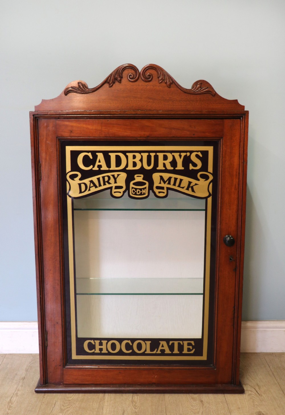 A lovely mahogany framed wall mounted display cabinet hand sign written for Cadburys Chocolate