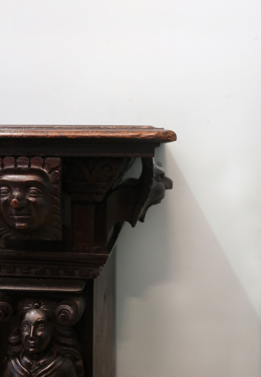 A dark carved Flemish oak side cabinet featuring detailed figural caryatids, relief mascarons, architectural door panels, and heavy bun feet. View VIII