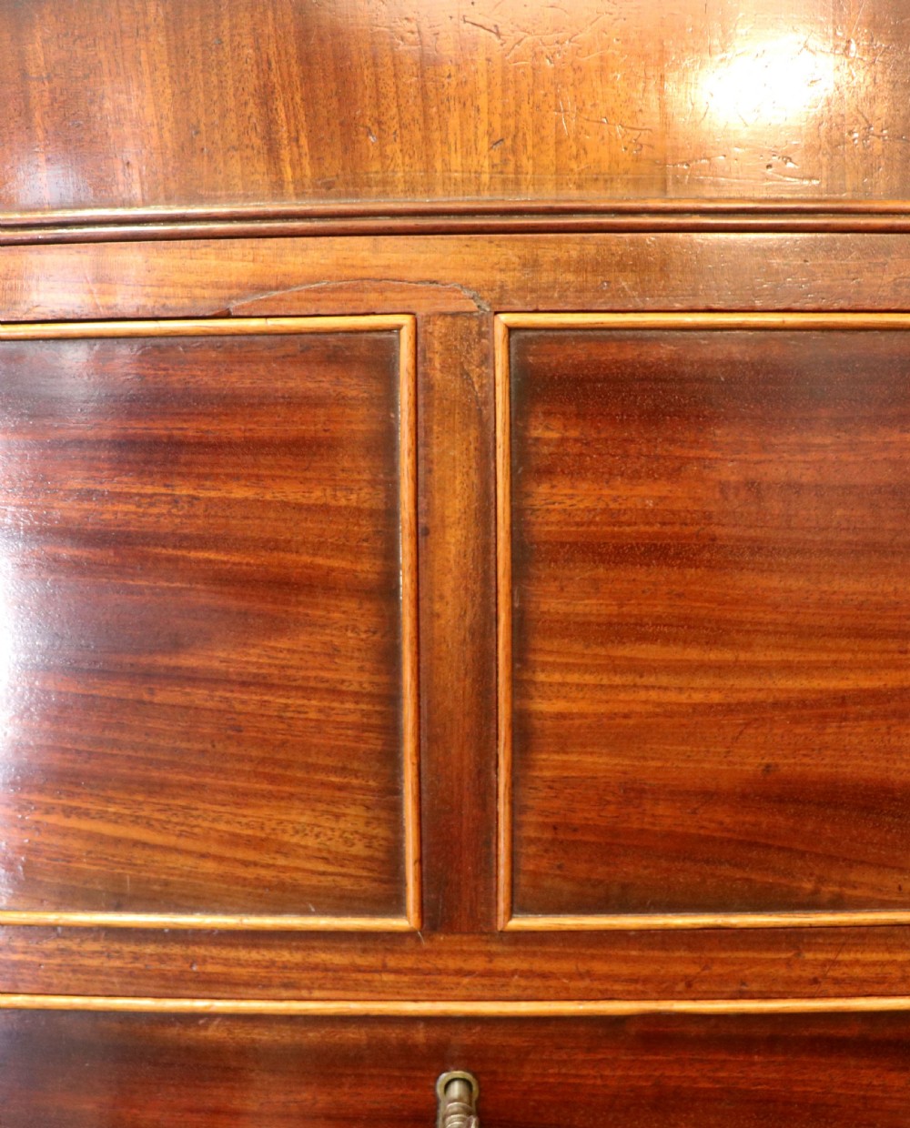 A nineteenth-century flame mahogany chest of drawers with two short and three long graduated drawers, decorative brass handles, and turned legs on castors. View XIII