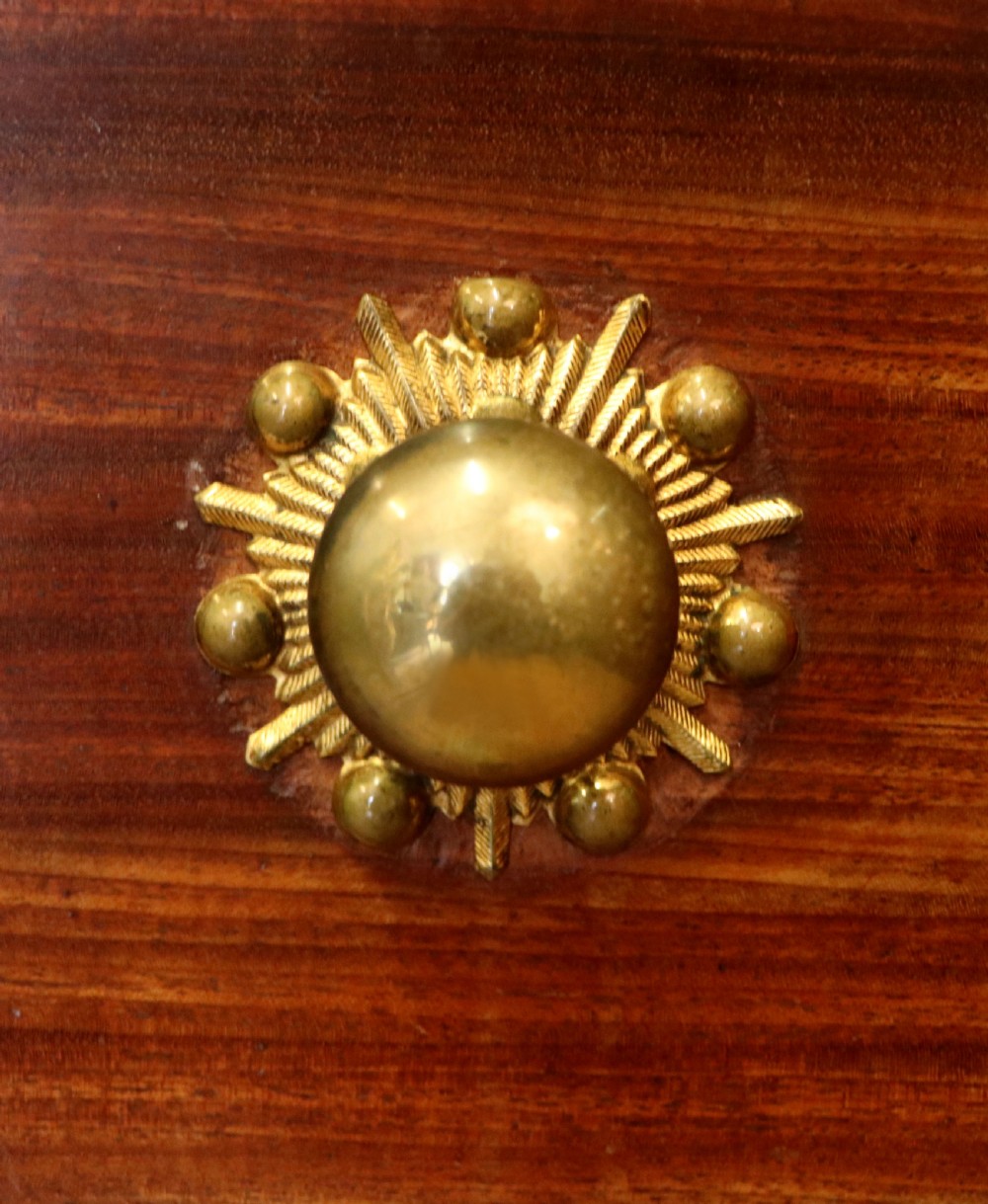 A nineteenth-century flame mahogany chest of drawers with two short and three long graduated drawers, decorative brass handles, and turned legs on castors. View XVI