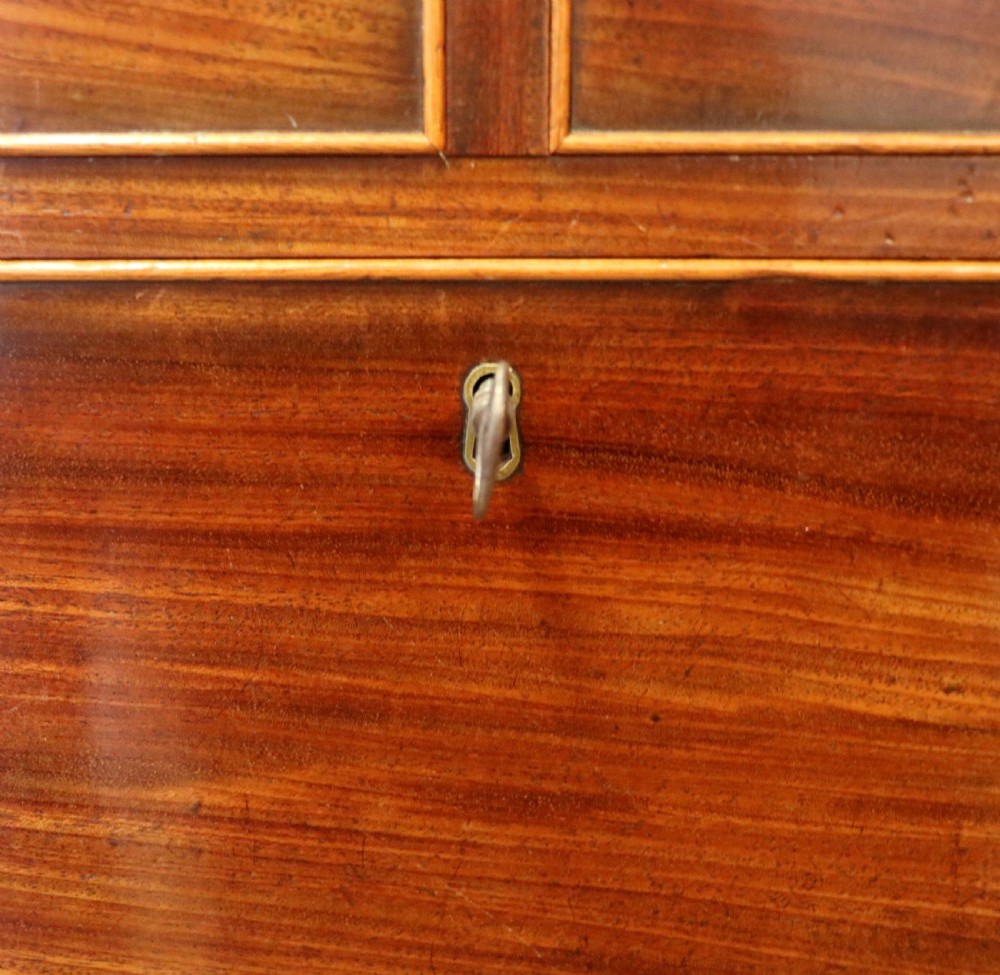 A nineteenth-century flame mahogany chest of drawers with two short and three long graduated drawers, decorative brass handles, and turned legs on castors. View XIX