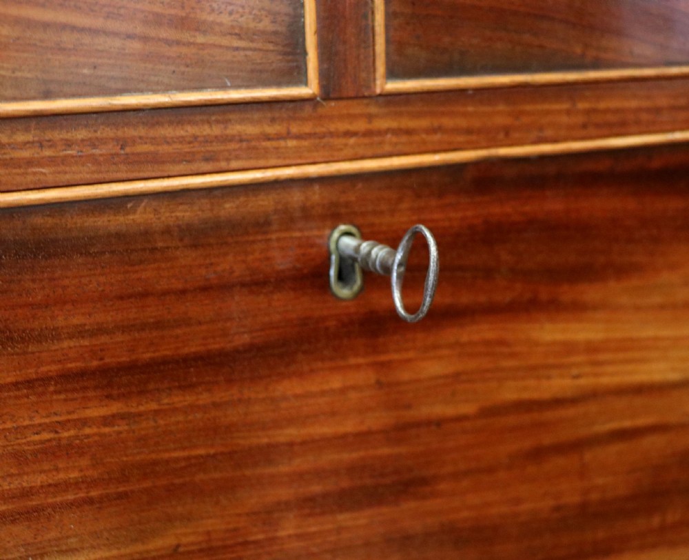 A nineteenth-century flame mahogany chest of drawers with two short and three long graduated drawers, decorative brass handles, and turned legs on castors. View XX