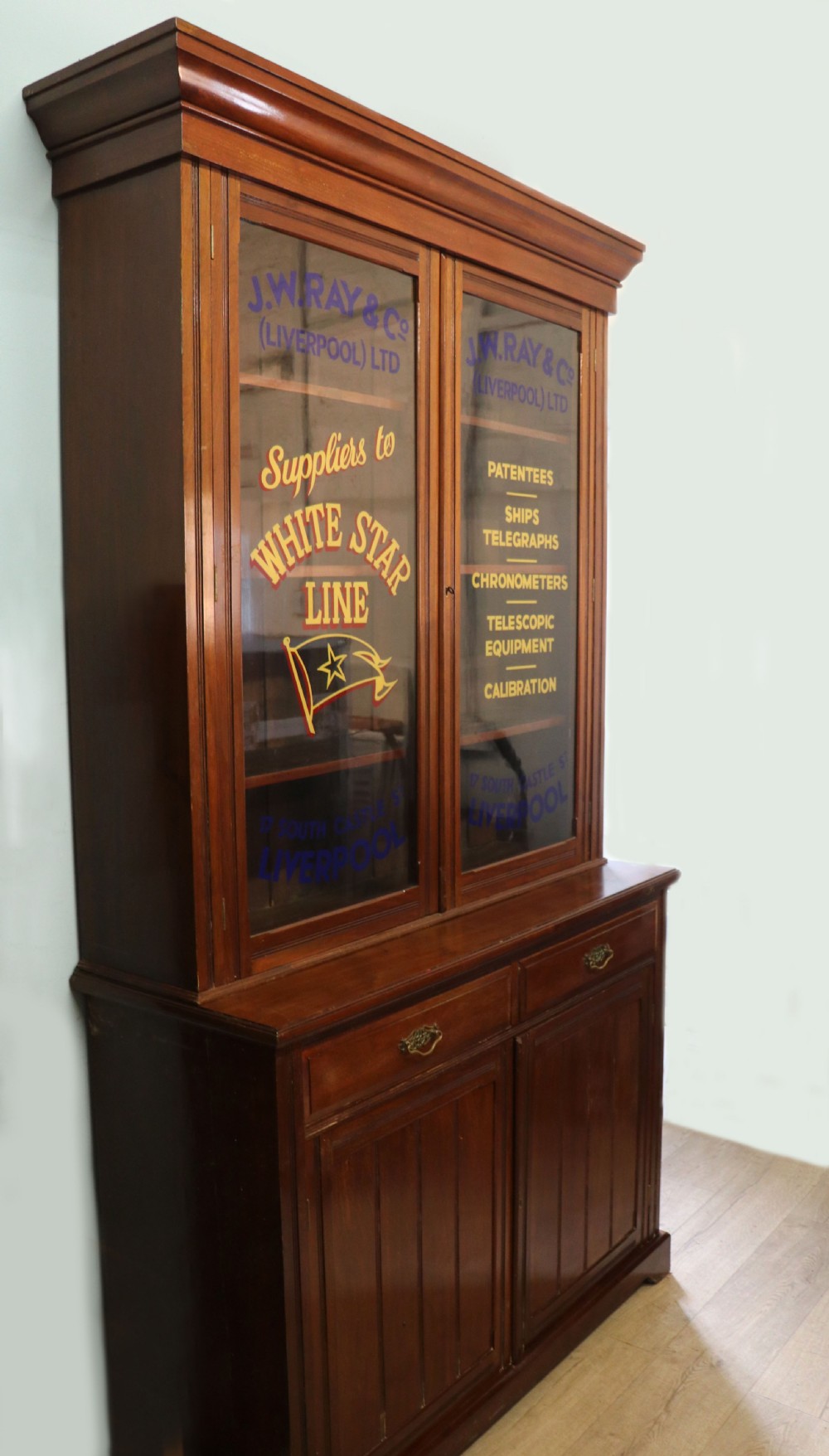 A late 19th-century walnut glazed display cabinet featuring two glass doors decorated with gilded signwriting above two drawers and a panelled base cupboard. View II
