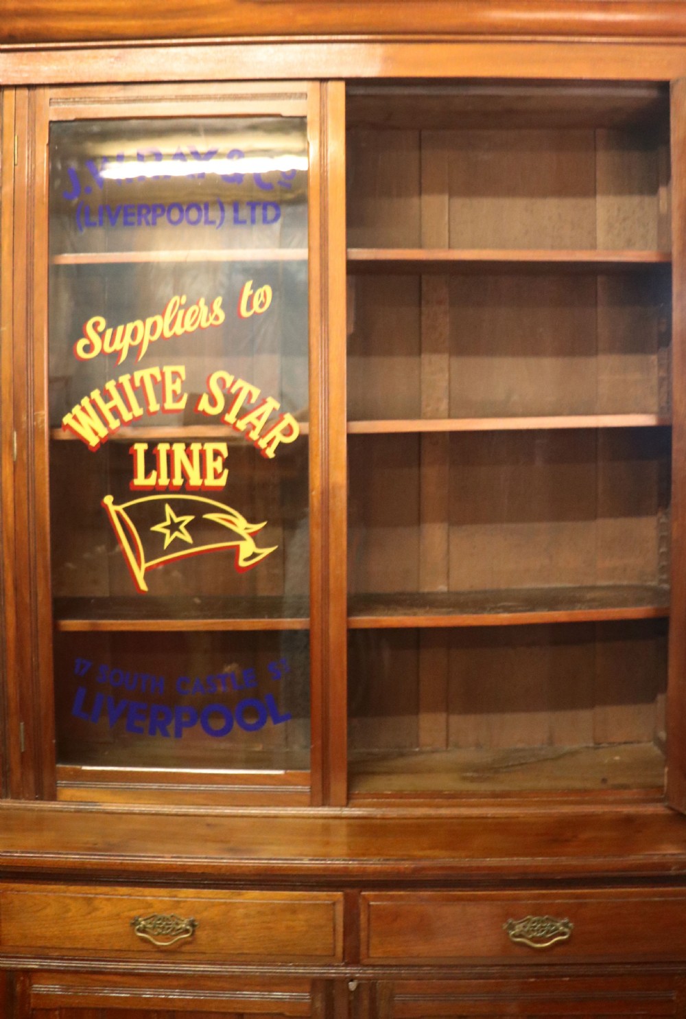A late 19th-century walnut glazed display cabinet featuring two glass doors decorated with gilded signwriting above two drawers and a panelled base cupboard. View IX