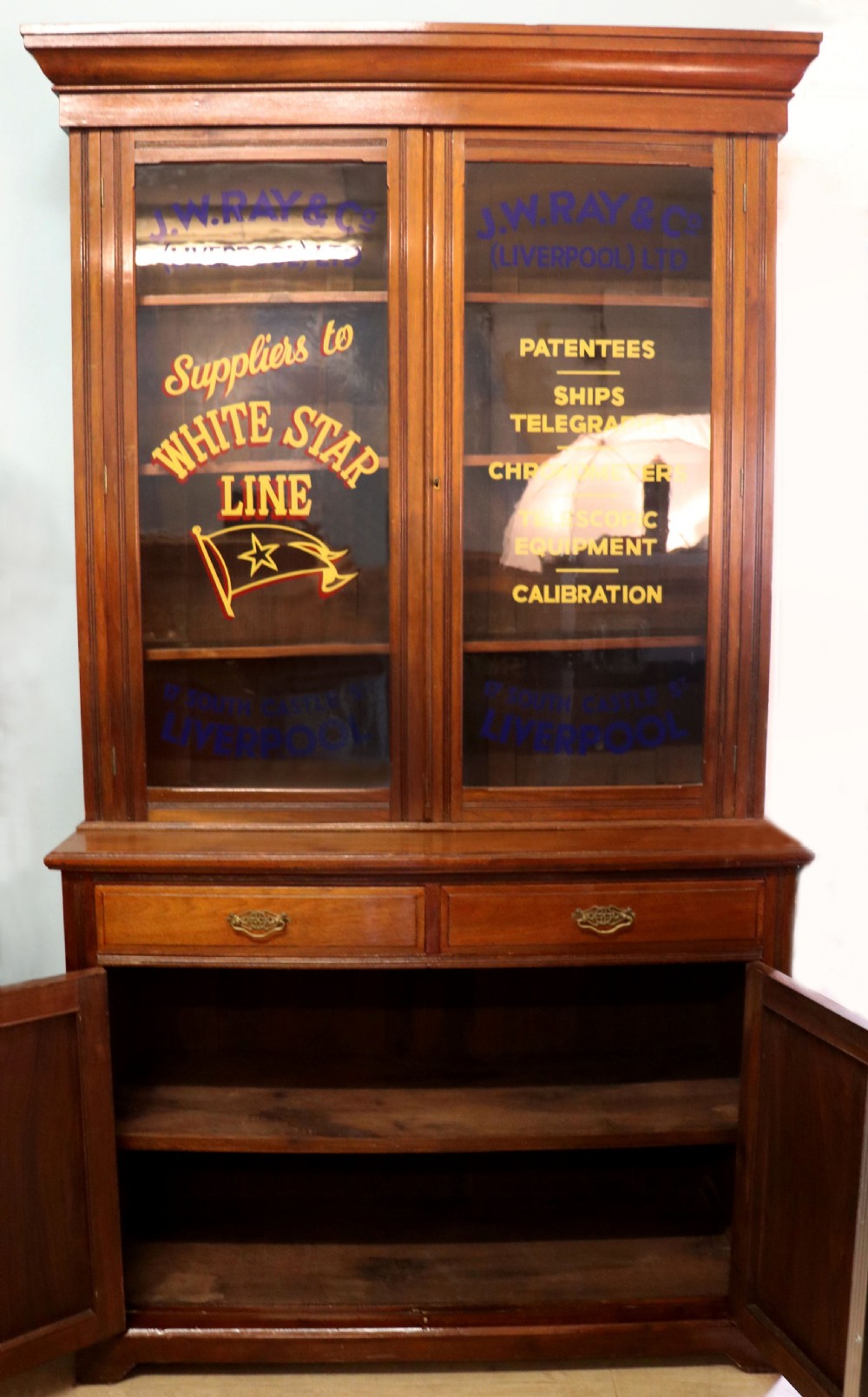 A late 19th-century walnut glazed display cabinet featuring two glass doors decorated with gilded signwriting above two drawers and a panelled base cupboard. View XI