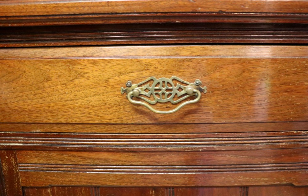 A late 19th-century walnut glazed display cabinet featuring two glass doors decorated with gilded signwriting above two drawers and a panelled base cupboard. View XIII