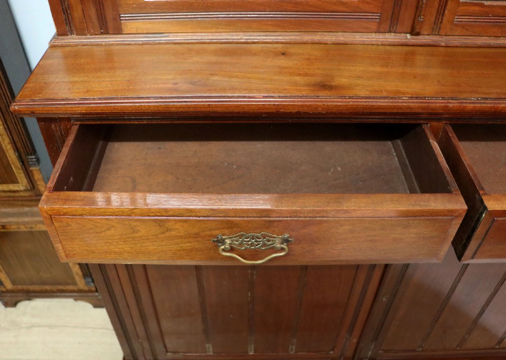 A late 19th-century walnut glazed display cabinet featuring two glass doors decorated with gilded signwriting above two drawers and a panelled base cupboard. View XIV