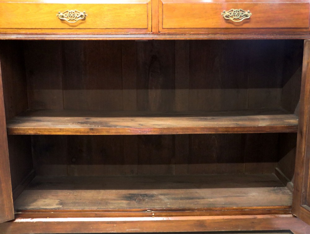 A late 19th-century walnut glazed display cabinet featuring two glass doors decorated with gilded signwriting above two drawers and a panelled base cupboard. View XVI