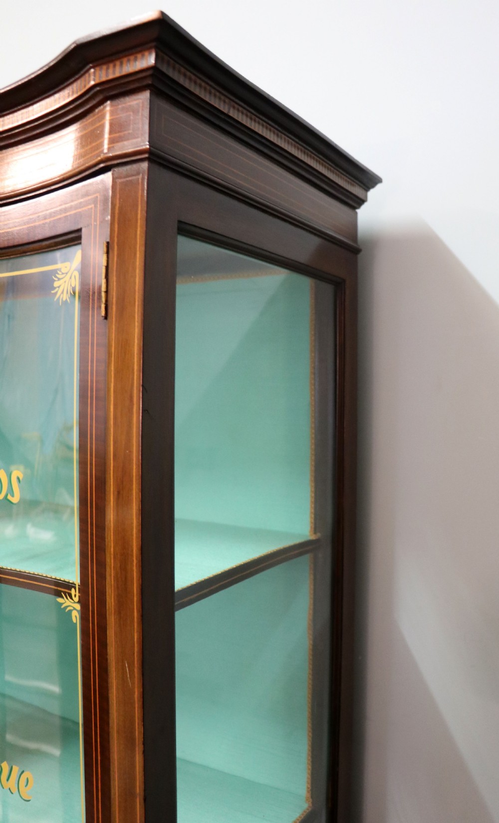 An Edwardian mahogany display cabinet featuring double glazed doors with gold sign-written perfume brand names against a turquoise painted interior. View XI