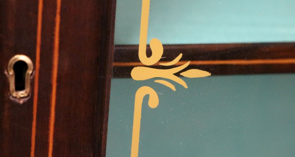 An Edwardian mahogany display cabinet featuring double glazed doors with gold sign-written perfume brand names against a turquoise painted interior. View XXII