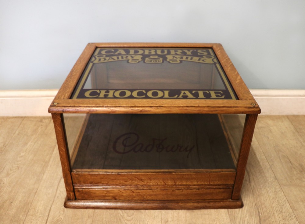 An early 20th-century oak countertop display cabinet featuring glazed panels and gold sign-written Cadburys Dairy Milk Chocolate lettering. View II