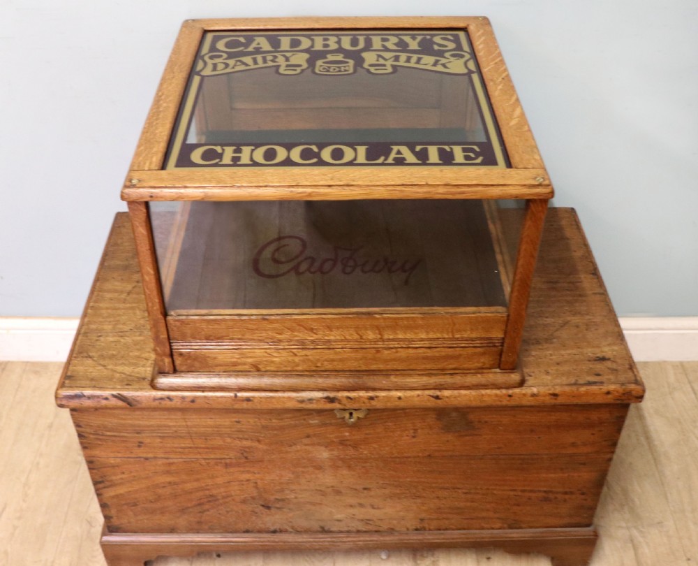 An early 20th-century oak countertop display cabinet featuring glazed panels and gold sign-written Cadburys Dairy Milk Chocolate lettering. View IV