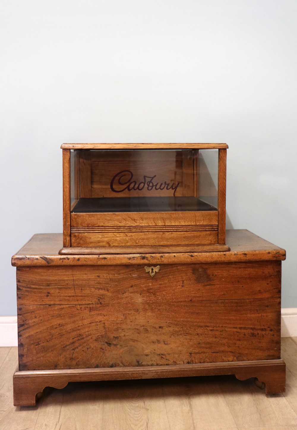 An early 20th-century oak countertop display cabinet featuring glazed panels and gold sign-written Cadburys Dairy Milk Chocolate lettering. View V