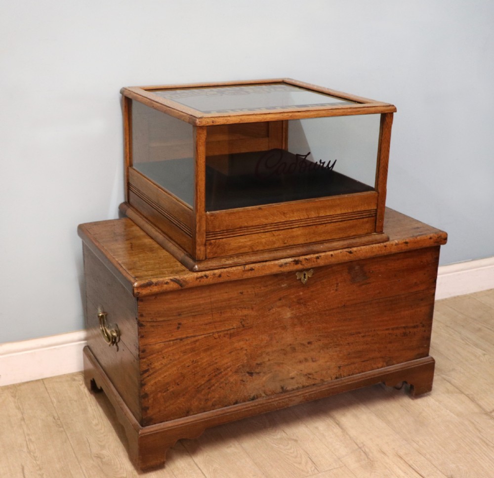 An early 20th-century oak countertop display cabinet featuring glazed panels and gold sign-written Cadburys Dairy Milk Chocolate lettering. View VI