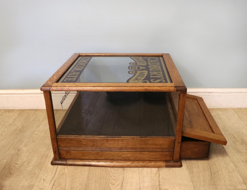 An early 20th-century oak countertop display cabinet featuring glazed panels and gold sign-written Cadburys Dairy Milk Chocolate lettering. View VII