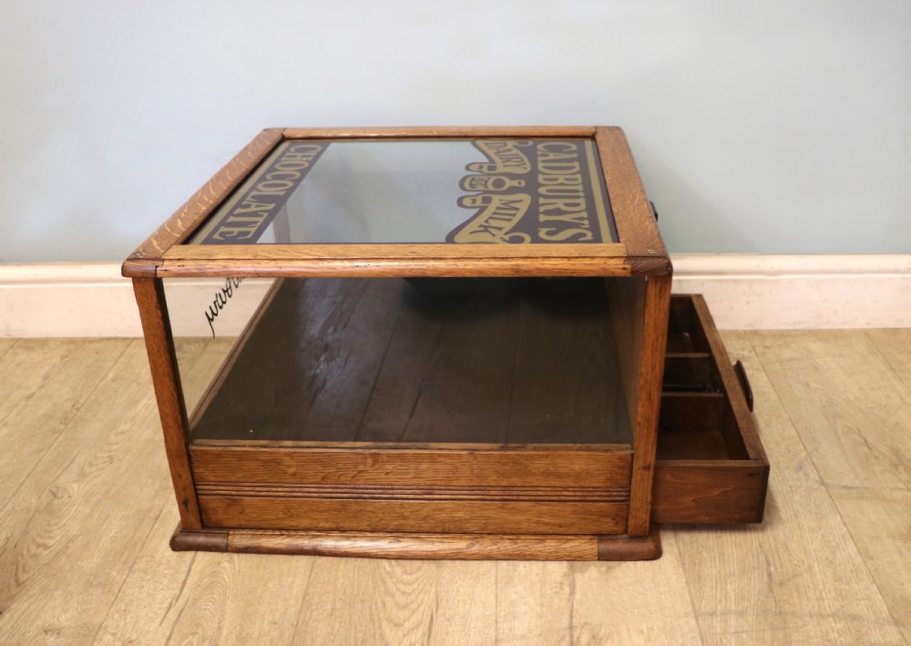 An early 20th-century oak countertop display cabinet featuring glazed panels and gold sign-written Cadburys Dairy Milk Chocolate lettering. View VIII