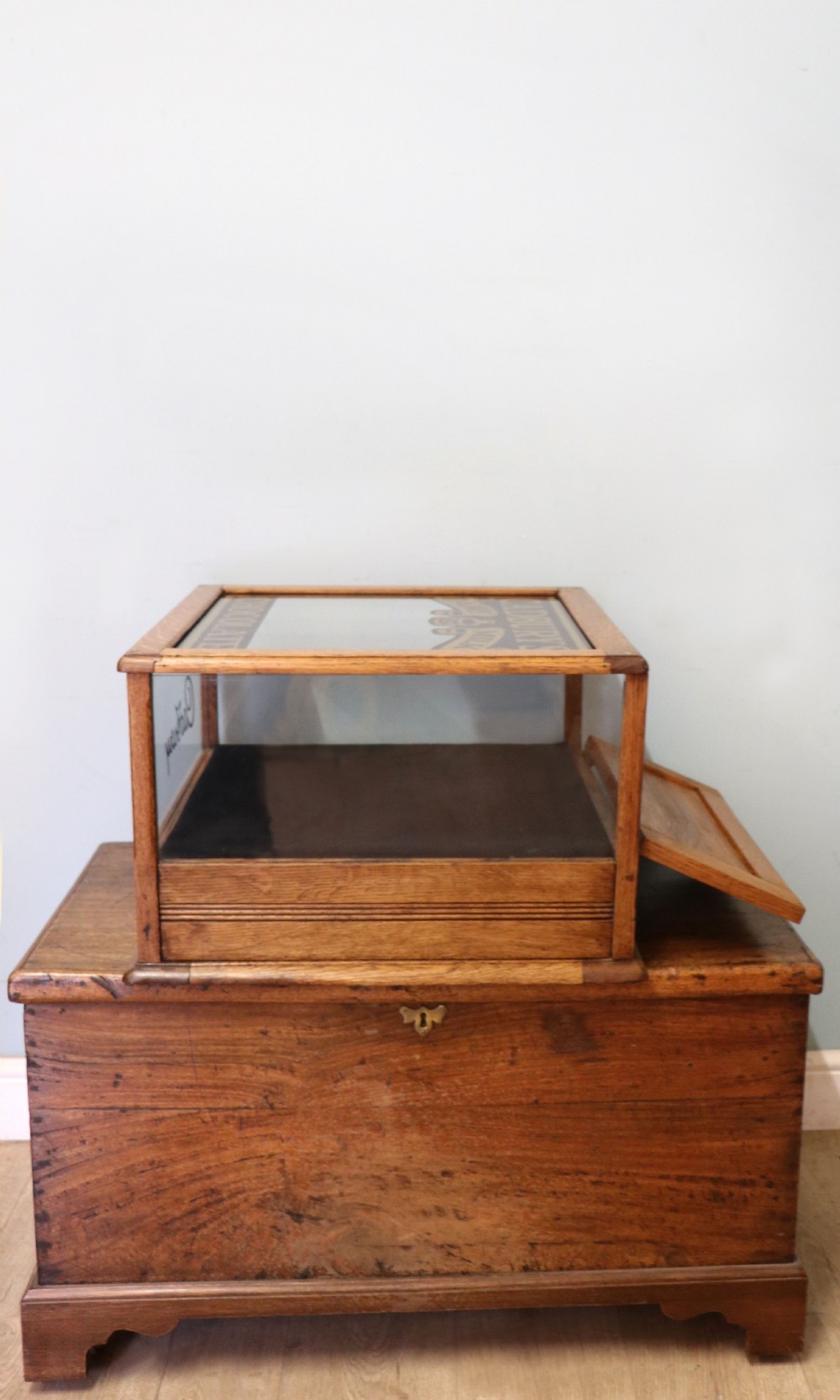 An early 20th-century oak countertop display cabinet featuring glazed panels and gold sign-written Cadburys Dairy Milk Chocolate lettering. View IX