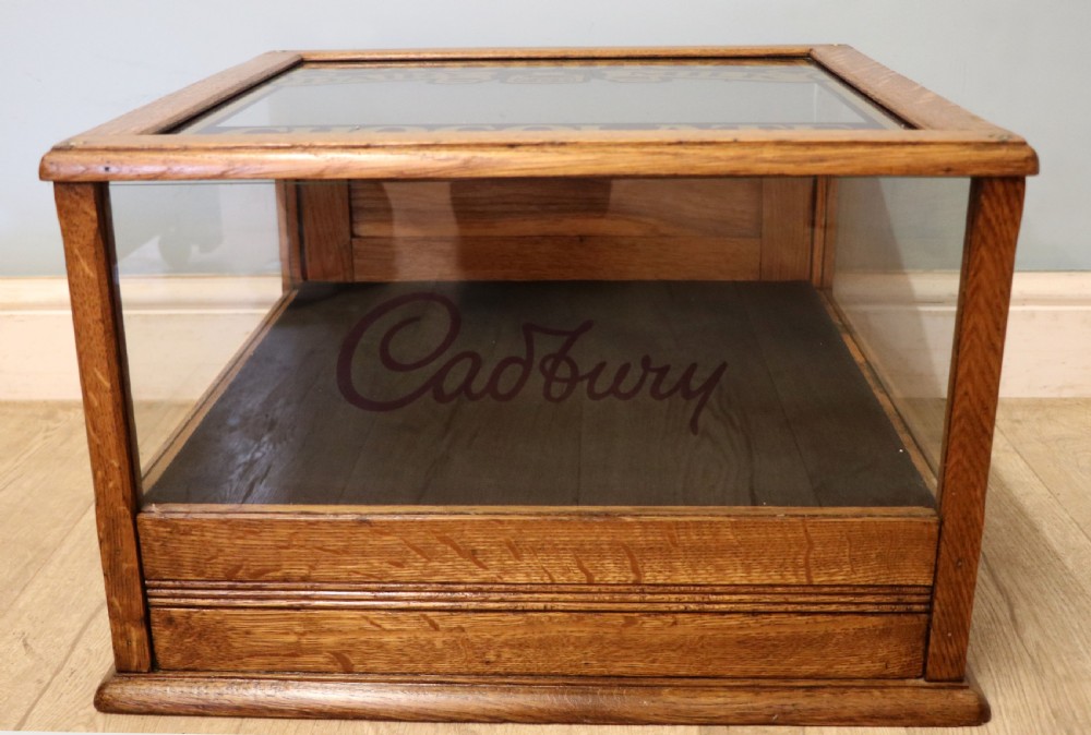 An early 20th-century oak countertop display cabinet featuring glazed panels and gold sign-written Cadburys Dairy Milk Chocolate lettering. View X