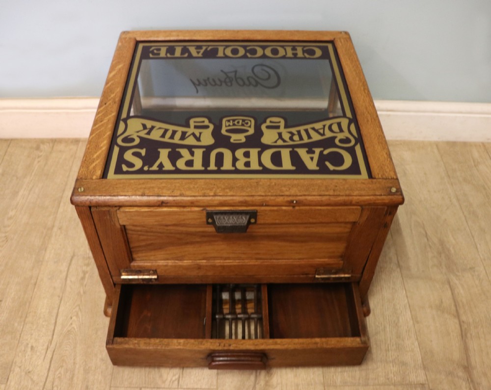 An early 20th-century oak countertop display cabinet featuring glazed panels and gold sign-written Cadburys Dairy Milk Chocolate lettering. View XI