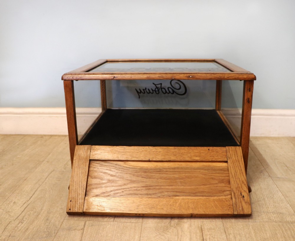 An early 20th-century oak countertop display cabinet featuring glazed panels and gold sign-written Cadburys Dairy Milk Chocolate lettering. View XIII