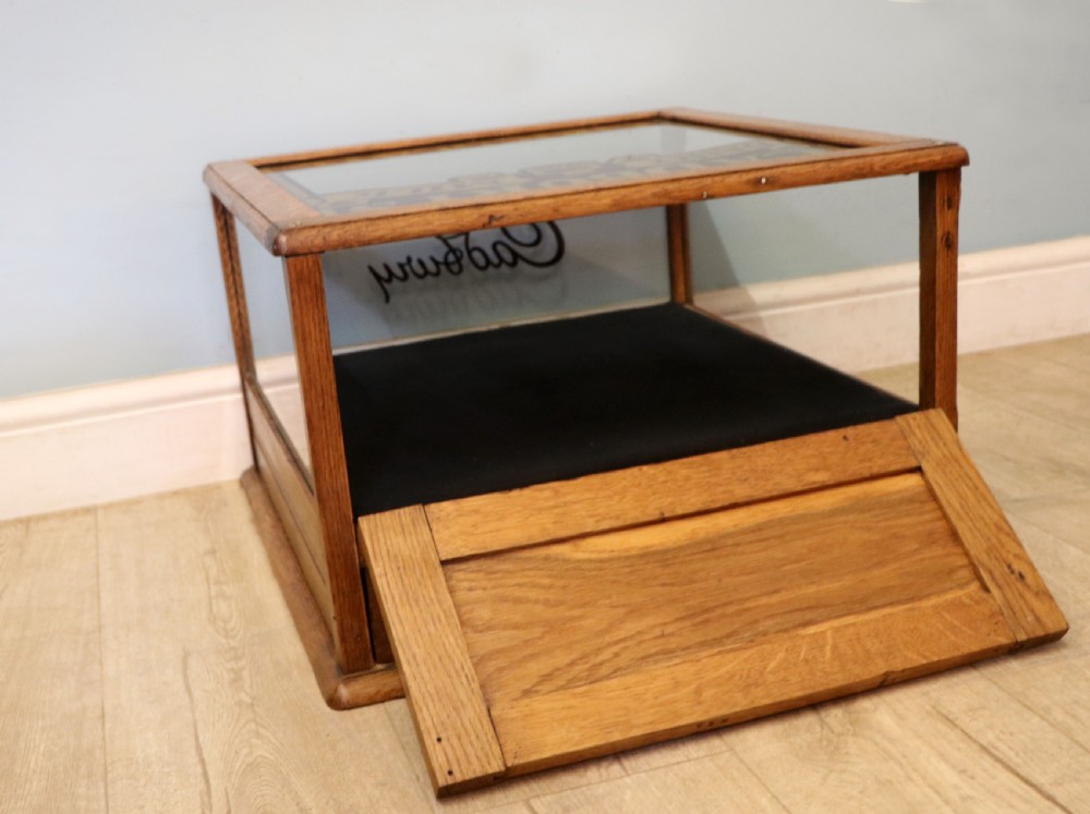 An early 20th-century oak countertop display cabinet featuring glazed panels and gold sign-written Cadburys Dairy Milk Chocolate lettering. View XV