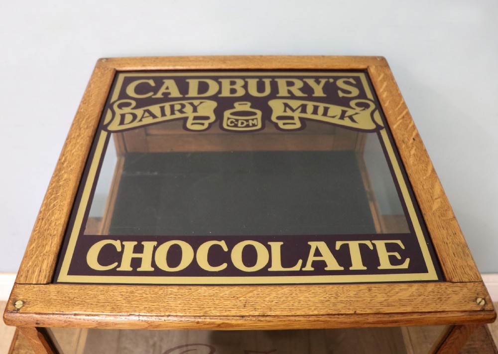 An early 20th-century oak countertop display cabinet featuring glazed panels and gold sign-written Cadburys Dairy Milk Chocolate lettering. View XVIII
